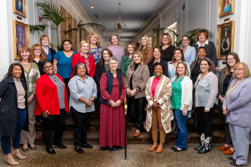 Inside group photo of about 25 women on stairs 